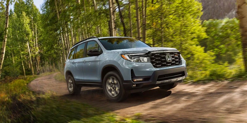 Front right view of a 2023 Honda Passport driving through a forest