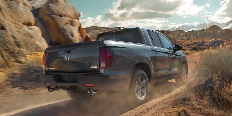 Rearview of a 2023 Honda Ridgeline driving down a dirt road