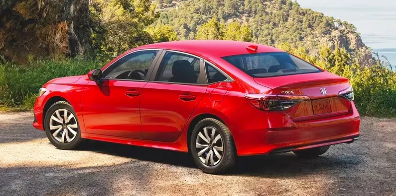 A red 2024 Civic Sedan parked on a dirt road.