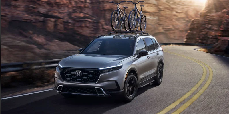 a 2024 Honda HR-V driving down a road with 2 bikes on the roof.