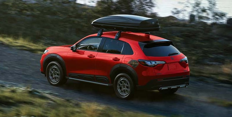 A photo of a red 2026 Honda HR-V driving down a dirt road.