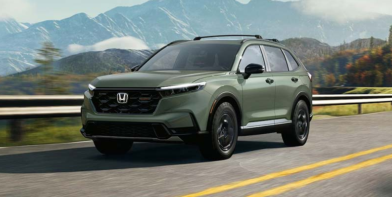 A green 2026 CR-V Hybrid driving down the road.