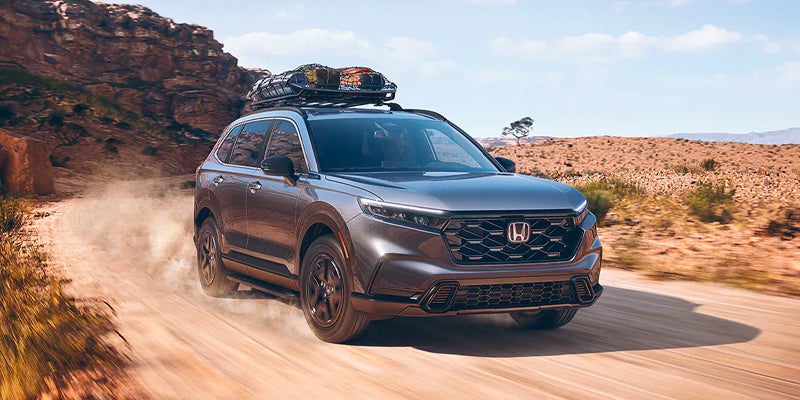 Front view of a 2023 Honda CR-V Hybrid driving down a desert road