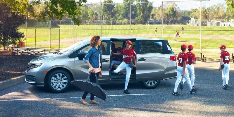 A family gets out of a 2024 Honda Odyssey parked outside a little league field