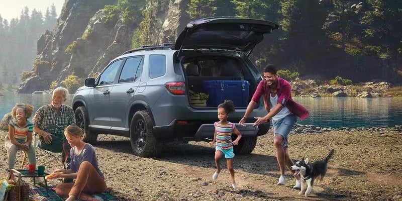 A family unpacks a 2024 Honda Pilot to camp next to a lake